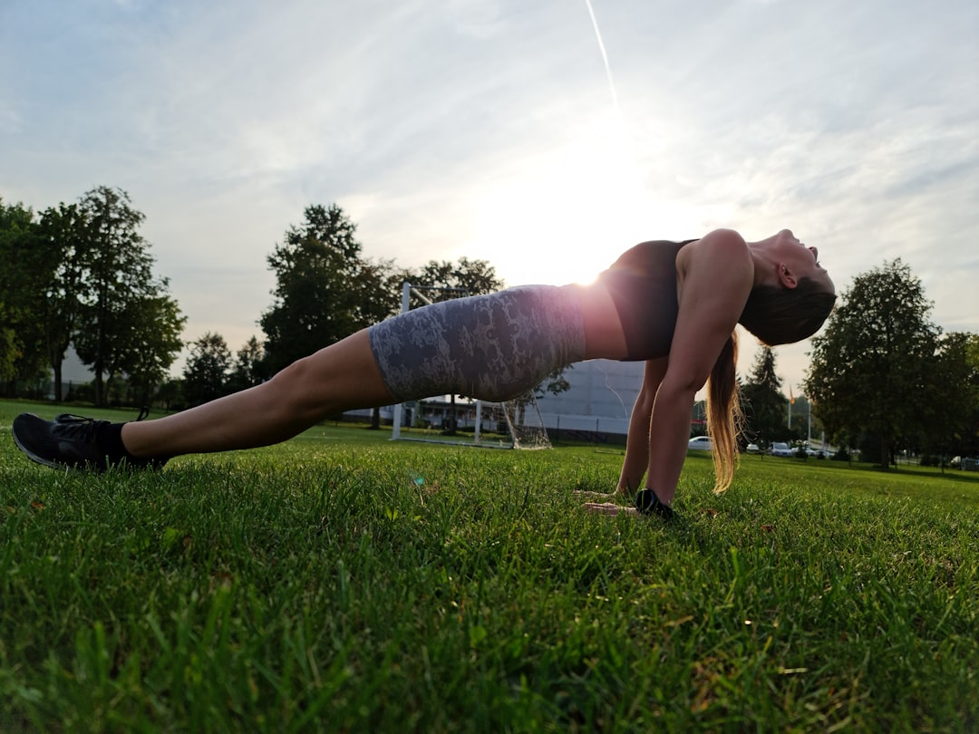 a woman is doing a push up in the grass