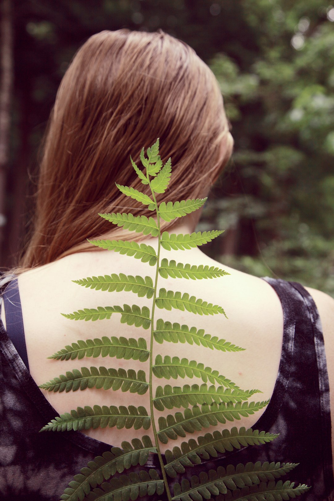 Photo by Tsunami Green woman in black and white tank top with green leaf on her back